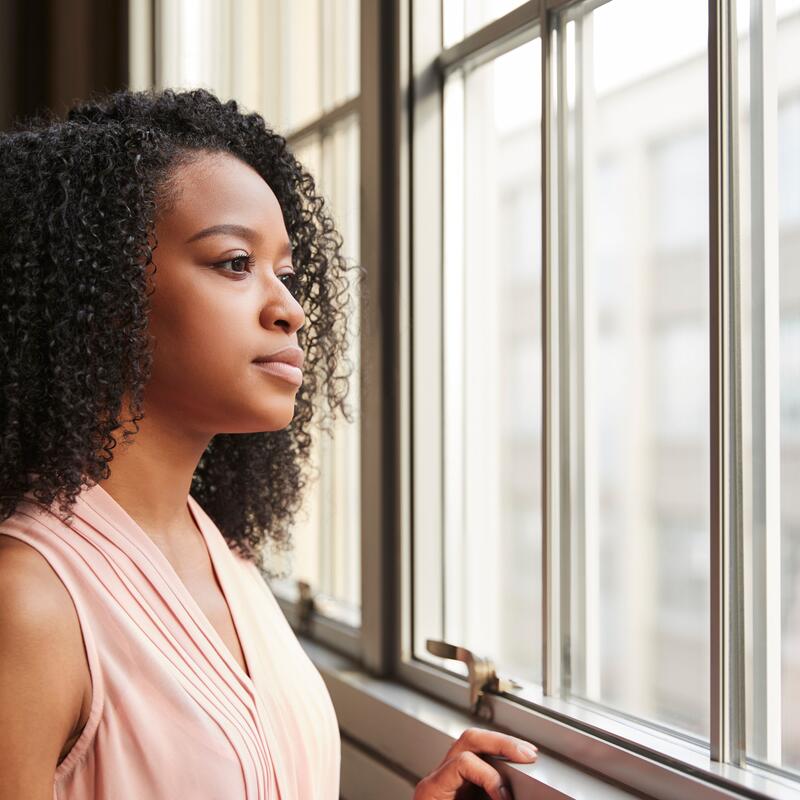 Black woman looking pensively out window